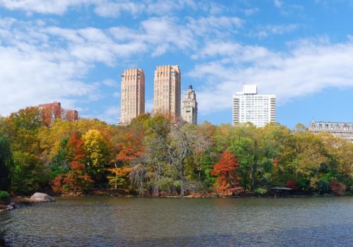 New York City Central Park panorama view in Autumn with Manhattan skyscrapers and colorful trees over lake with reflection.